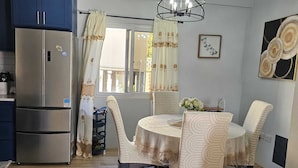 A modern kitchen with a stainless steel refrigerator, a dining table with chairs, and a chandelier. - House of the Three Companions (Gros Islet)