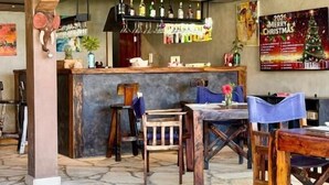 A bar area with a stone floor, wooden furniture, and a Christmas-themed poster. - Di Milo Boutique Hotel (Kiwengwa)