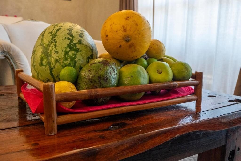 Un puesto de frutas de madera con sandía y manzanas sobre una mesa.