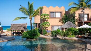 A resort with a pool, palm trees, and a beach view.