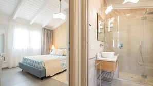 A modern hotel room with a bed, bedside table, and a glass-enclosed shower area. - Holiday Home 'Borgo Myricae - Calendula' with Sea View, Wi-Fi and Air Conditioning (Chia)