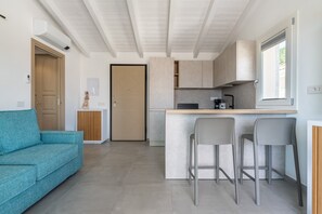 Een moderne keuken met een centraal eiland, barkrukken en een bank.