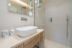 A modern bathroom with a large white sink, a mirror, a shower, and a toilet. - Holiday Home 'Borgo Myricae - Scilla Bianca' with Shared Pool, Wi-Fi and Air Conditioning (Chia)