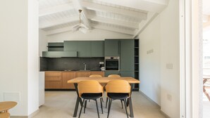 Una cocina moderna con comedor, que incluye una mesa con sillas, un ventilador de techo y electrodomésticos integrados.