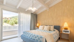 Un dormitorio con una cama grande, dos lámparas de noche, vistas a través de una puerta corredera y una pared de madera.