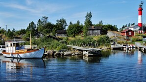 A coastal village with a lighthouse, wooden houses, and a dock with a boat. - Original Sokos Hotel Kaarle (Kokkola)