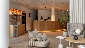 Un moderno vestíbulo de hotel con mostrador de recepción, zona de estar y una planta grande.