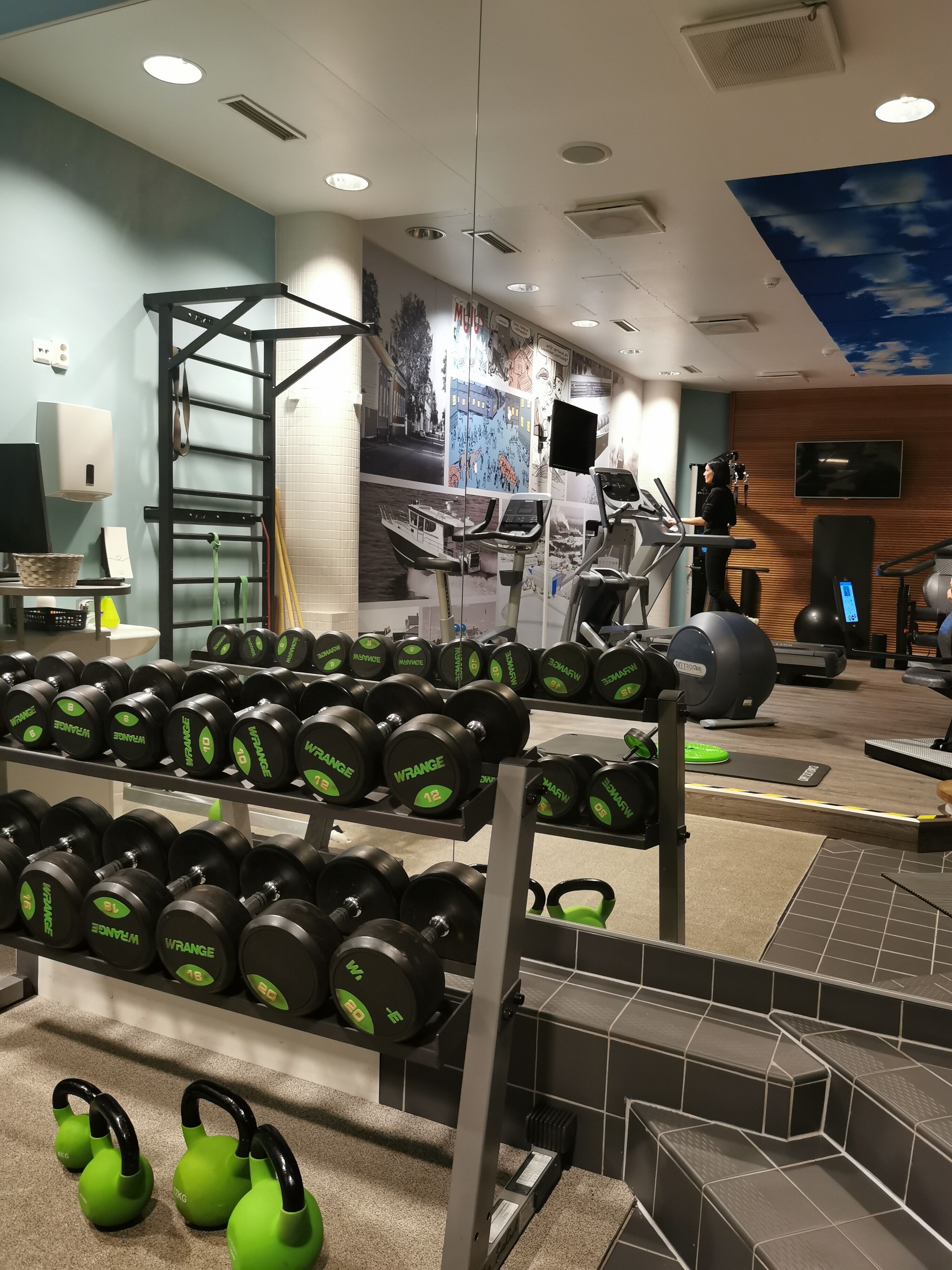 Un gimnasio con cintas de correr, bicicletas estáticas y equipos de levantamiento de pesas.
