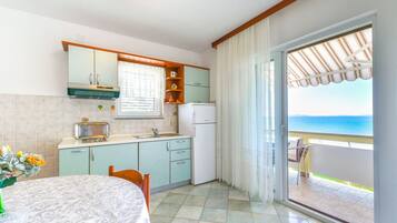 A kitchen with a view of the sea, a dining table, and a balcony with a chair.