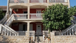 Ein mehrstöckiges Gebäude mit roter Fassade, weißen Balkonen und einem steinernen Eingang.