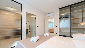 Habitación de hotel con cama, un espejo grande, un armario y un baño visible a través de una puerta abierta.