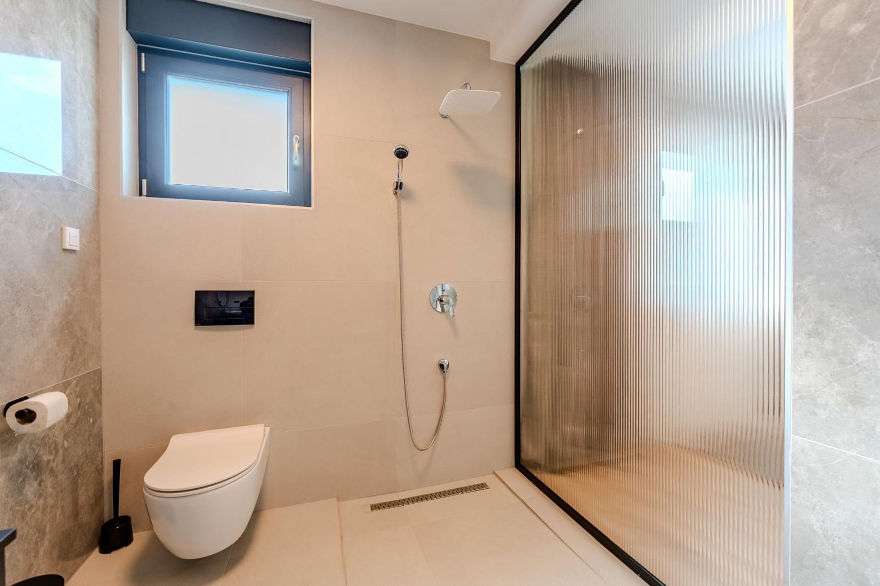 A modern bathroom with a toilet, a shower, and a glass-enclosed shower area.