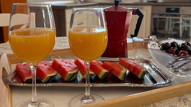 A tray with two glasses of orange juice, watermelon slices, and a bowl of grapes on a table in a kitchen. - Beautiful Apartment Bodulo 3 (Povljana)