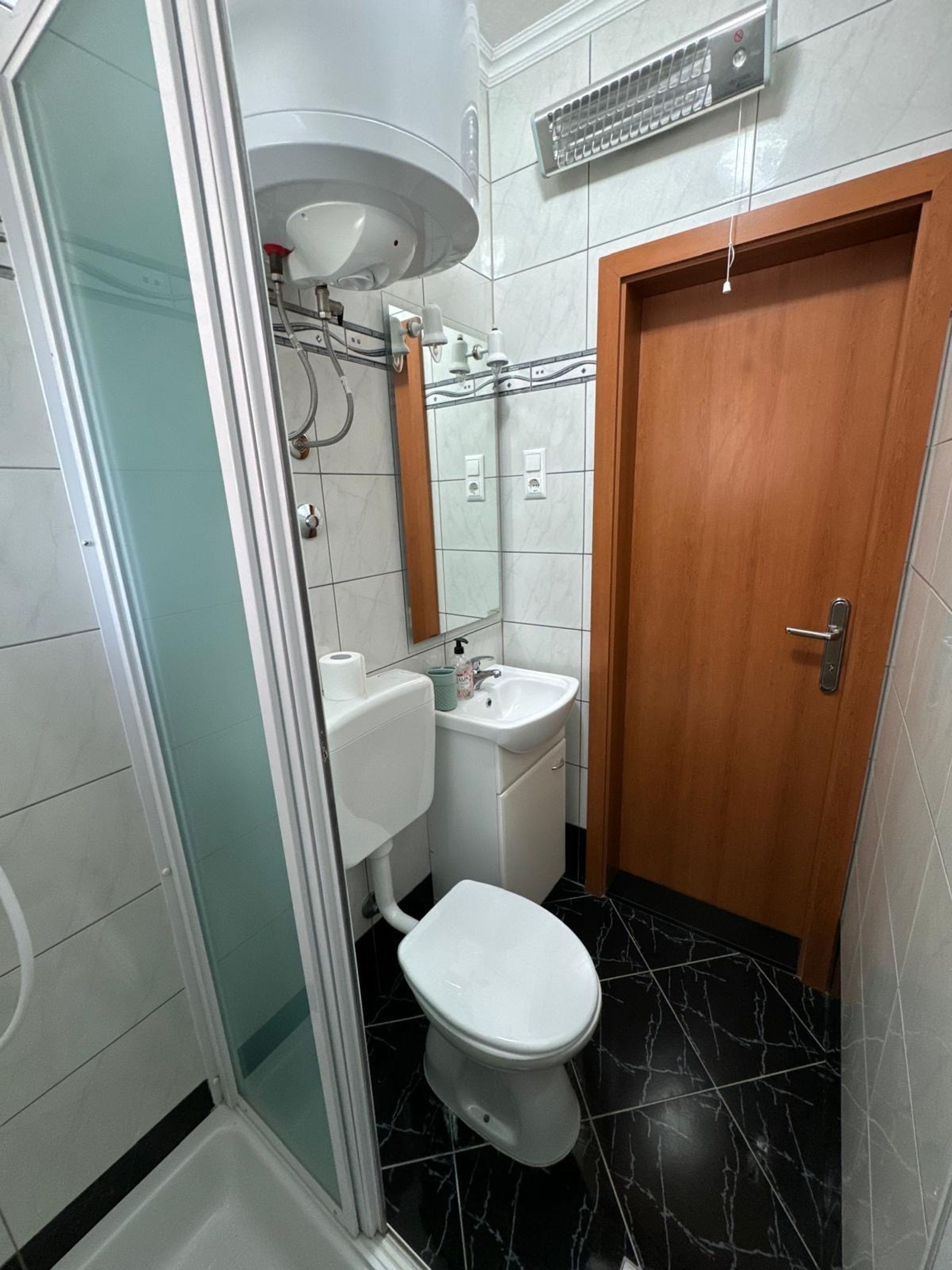 Une petite salle de bain comprenant des toilettes, un lavabo et un espace douche.