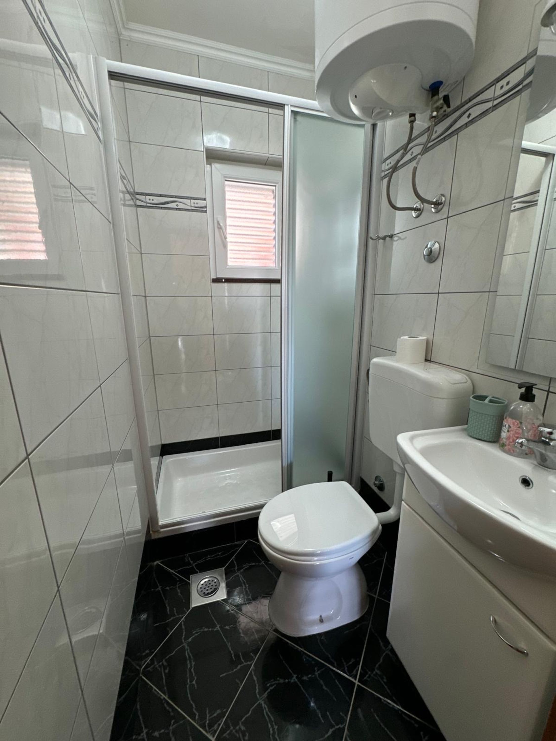 Ein kleines Badezimmer mit Toilette, Waschbecken und Dusche.