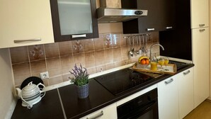 A modern kitchen with a black countertop, white cabinets, and a stainless steel range hood. - Beautiful Apartment Bodulo 1 (Povljana)