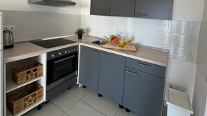 Una cocina moderna con armarios grises, una estufa negra y un lavamanos de acero inoxidable.