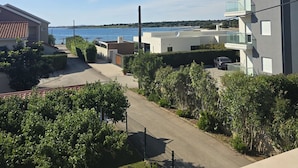 Une rue résidentielle bordée de maisons, offrant une vue dégagée sur la mer et entourée d’une végétation luxuriante.