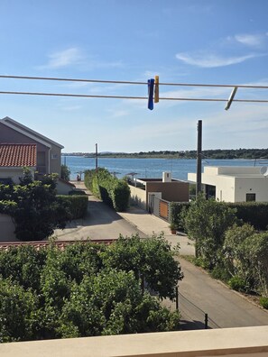 A residential area with a view of the sea, a paved pathway, and a building with a tiled roof. - Studio Apartment Lea (Nin)
