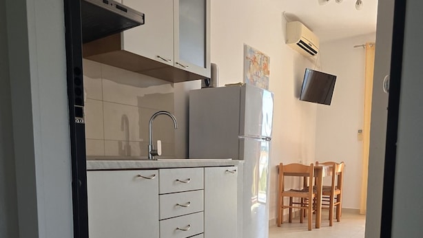 Une cuisine moderne avec des meubles blancs, un four encastré et un coin repas doté de chaises en bois.