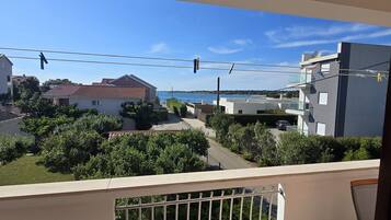 Un balcón con vista a una zona residencial, que incluye casas y una masa de agua.