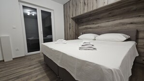 A bedroom with a bed, wooden headboard, and a sliding door leading to a balcony. - Villa Pauliana in Povljana (Povljana)