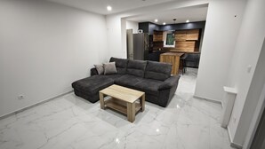 A modern living room with a sectional sofa, a wooden coffee table, and a kitchen area in the background. - Villa Pauliana in Povljana (Povljana)