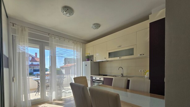A modern kitchen with a dining area, large windows, and a view of the outside. - Apartment Marcela in Zaton (Nin)