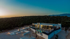 A modern villa with a swimming pool, outdoor seating, and a view of the surrounding forest. - Modern Villa Porta in Novalja (Novalja)