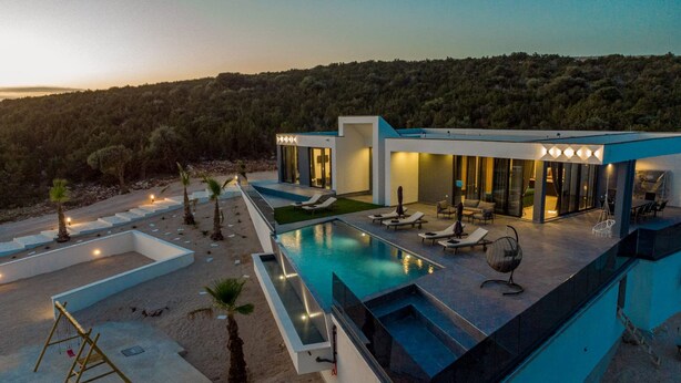 A modern villa with a swimming pool, outdoor seating, and a view of the surrounding forest. - Modern Villa Porta in Novalja (Novalja)