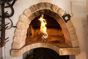 A stone-built fireplace with a fire burning inside. - Beachfront Holiday Home With Pool Mami (Marina)