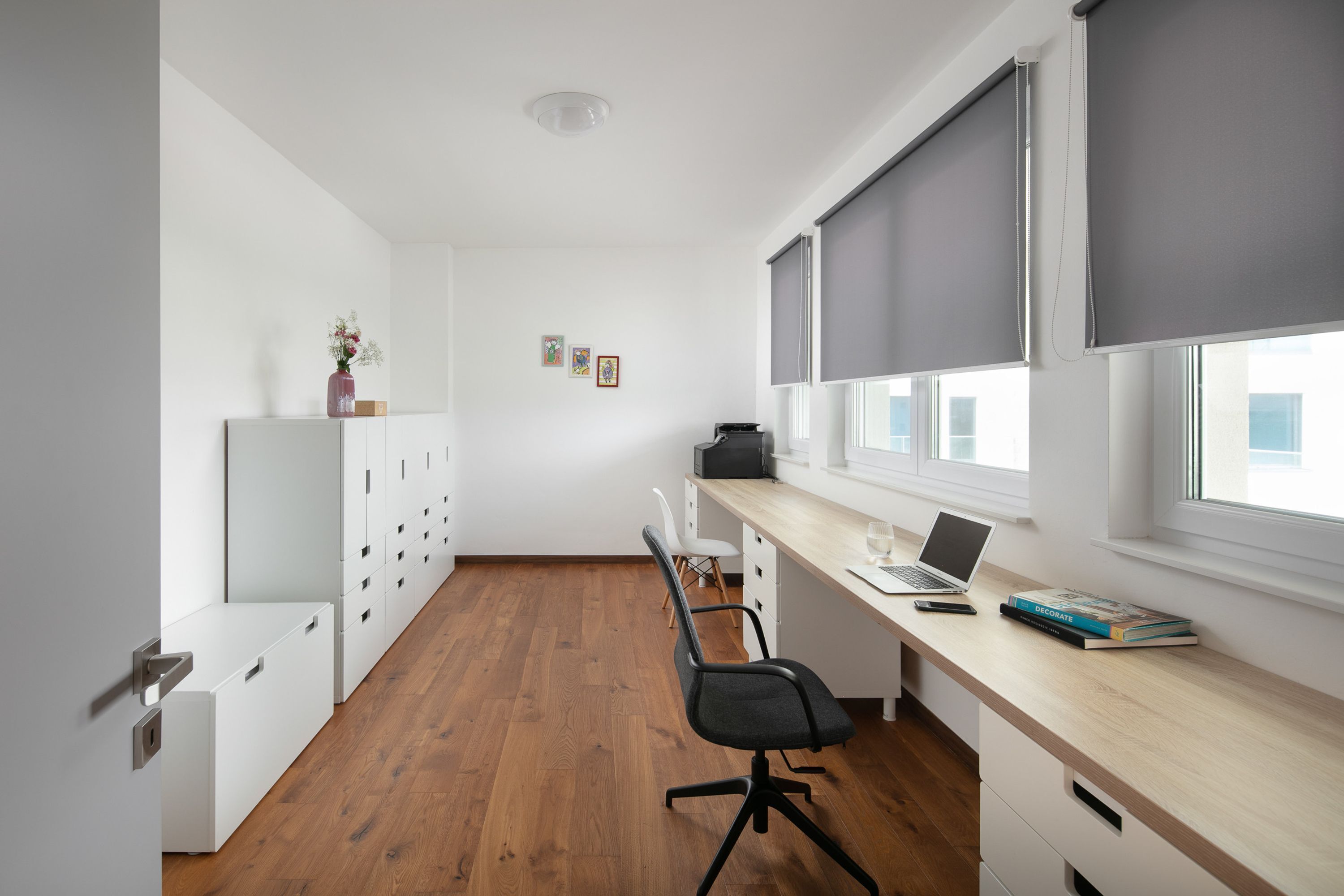Een moderne kantoorruimte met een houten bureau, een stoel, een laptop en een boekenplank.
