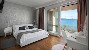 A modern bedroom with a large bed, a desk, and a view of the sea. - Beautiful Villa Sale (Sukosan)