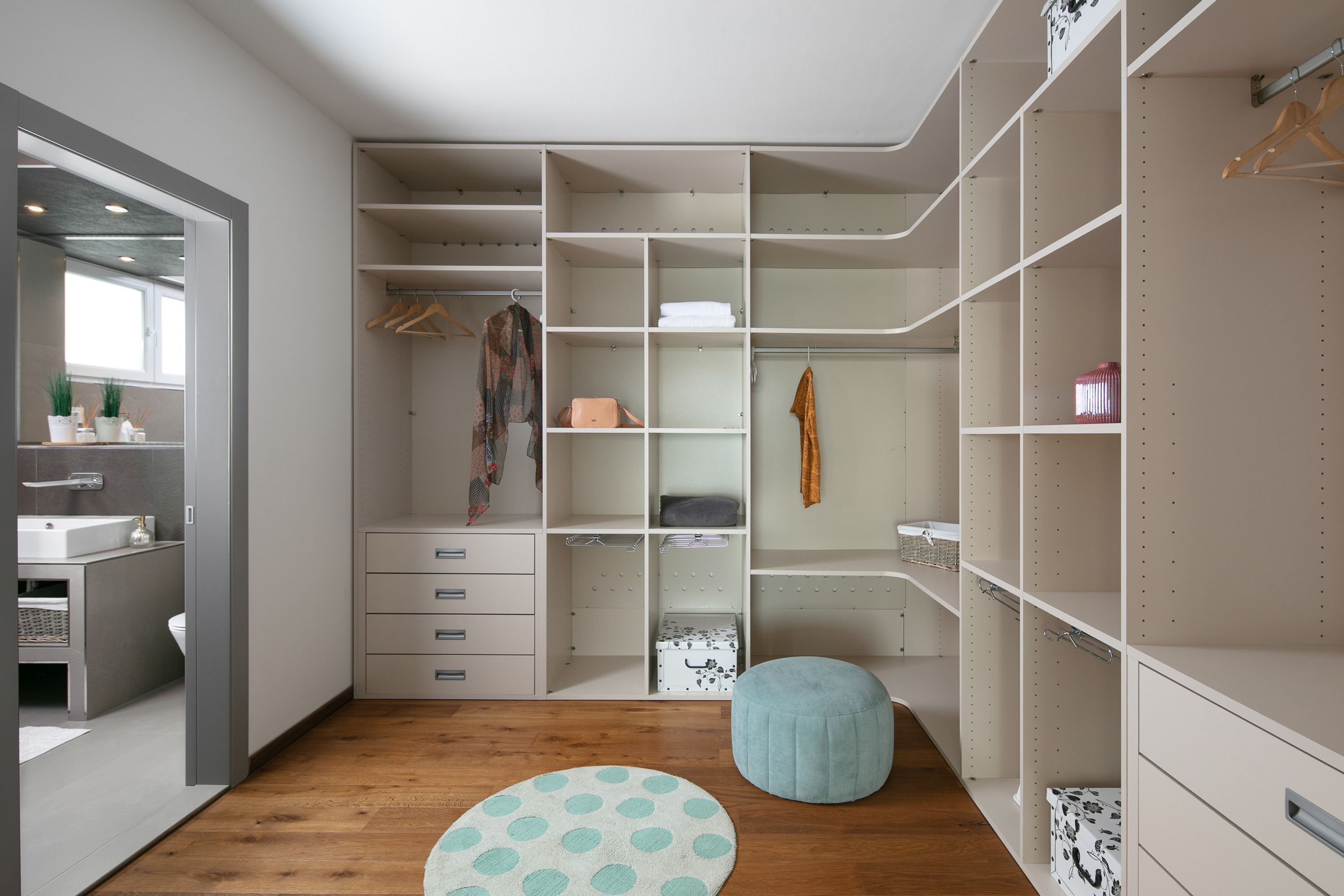 Een moderne inloopkast met open planken, ophangruimte en lades.