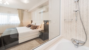 Quarto moderno com chuveiro em gabinete de vidro, uma cama grande com travesseiros e um ar condicionado integrado.