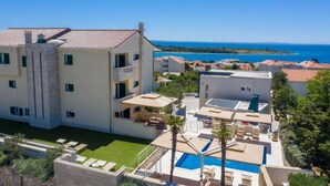 Um hotel com vários andares, piscina e vista para o mar.