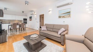 A modern living room with a sofa, coffee table, and a dining area with chairs and a table. - Sargas Suite 3 With Pool View (Novalja)