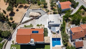 An aerial view of a residential area with a large house featuring a swimming pool, a curved driveway, and surrounding greenery. - Sargas Suite 3 With Pool View (Novalja)