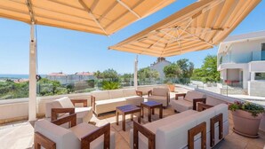 A rooftop terrace with outdoor seating, a large umbrella, and a view of the sea and buildings. - Sargas Suite 3 With Pool View (Novalja)