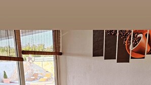A cozy living room with a sectional sofa, a coffee table with books and a vase, and a window with blinds. - Family Home Iskra in Bulic (Benkovac)