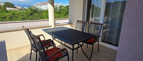 Une terrasse couverte avec une table et des chaises, une porte-fenêtre coulissante et une vue sur les environs.