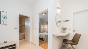 A modern hotel room with a bed, a vanity with a mirror, a chair, and a small desk. - Sargas Suite 4 With Garden View (Novalja)