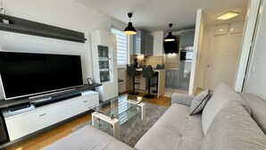 A modern living room with a flat-screen TV, a glass coffee table, and a grey sofa. - Apartment Restart in Zadar (Zadar)