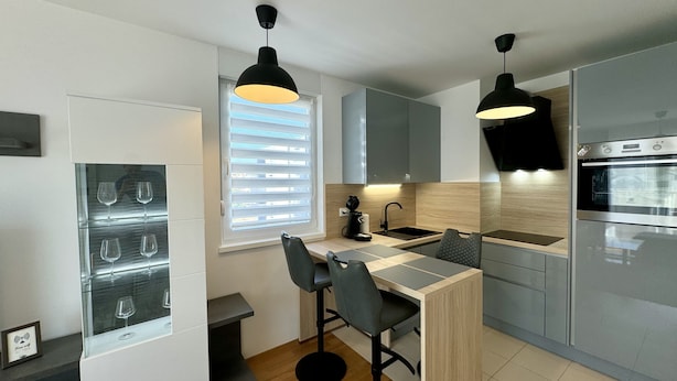 A modern kitchen with a built-in wine cooler, a bar area with stools, and a large oven. - Apartment Restart in Zadar (Zadar)