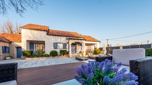 Una casa moderna con tetto in tegole, patio lastricato e area salotto all'aperto.