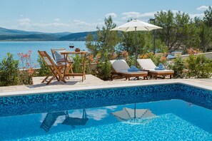 Ein Poolbereich mit Liegestühlen und einem Tisch mit Blick auf einen See.
