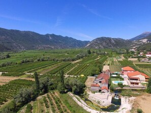 A rural landscape with vineyards, a small building with a red roof, and mountains in the background. - Holiday Home Nadalina (Vrgorac)