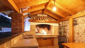 Una cocina rústica con horno de ladrillo, vigas de madera, paredes de piedra y encimera de piedra.