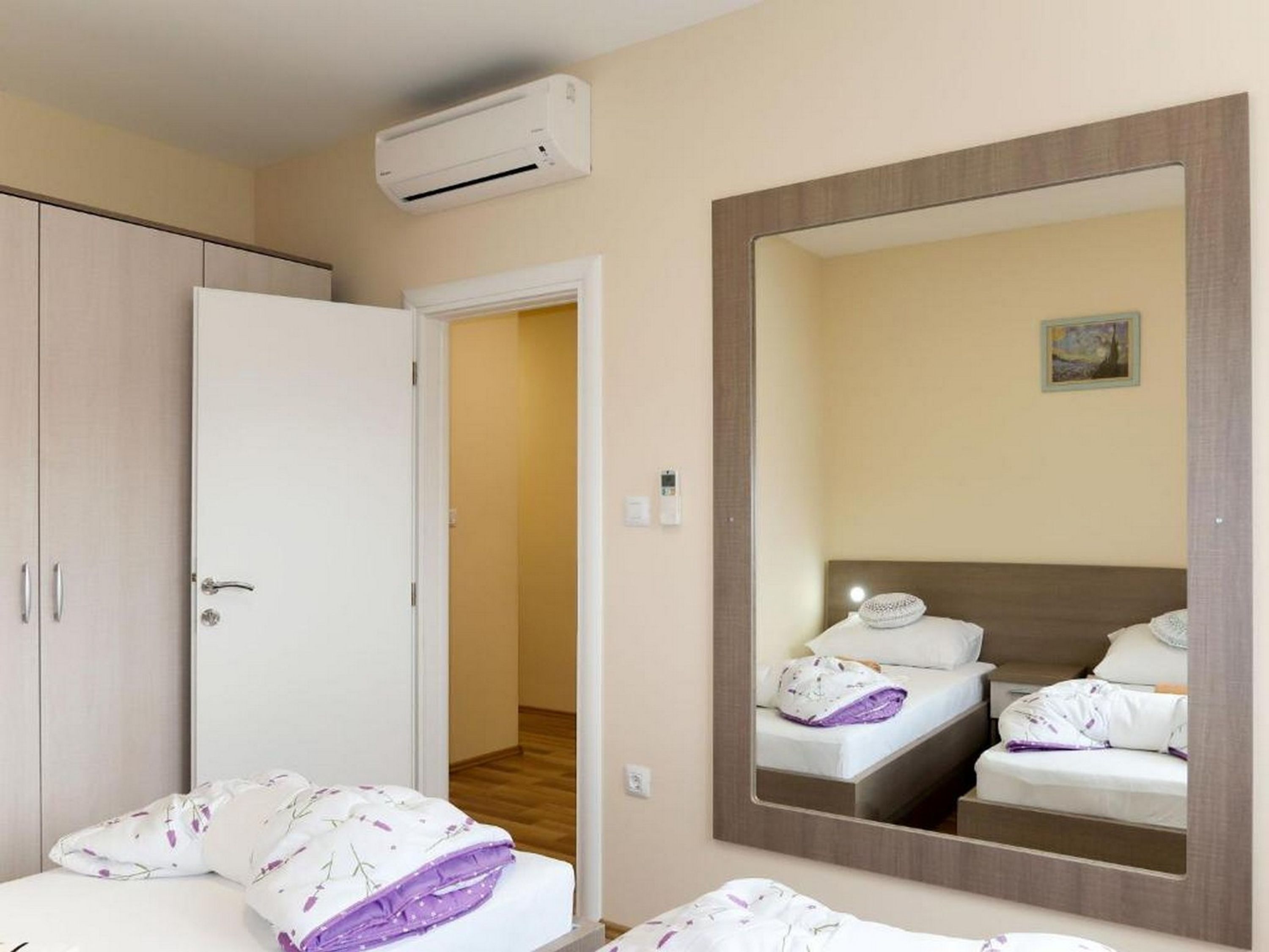 Une chambre d’hôtel équipée d’un lit, d’une armoire, d’un miroir et d’un appareil de climatisation.
