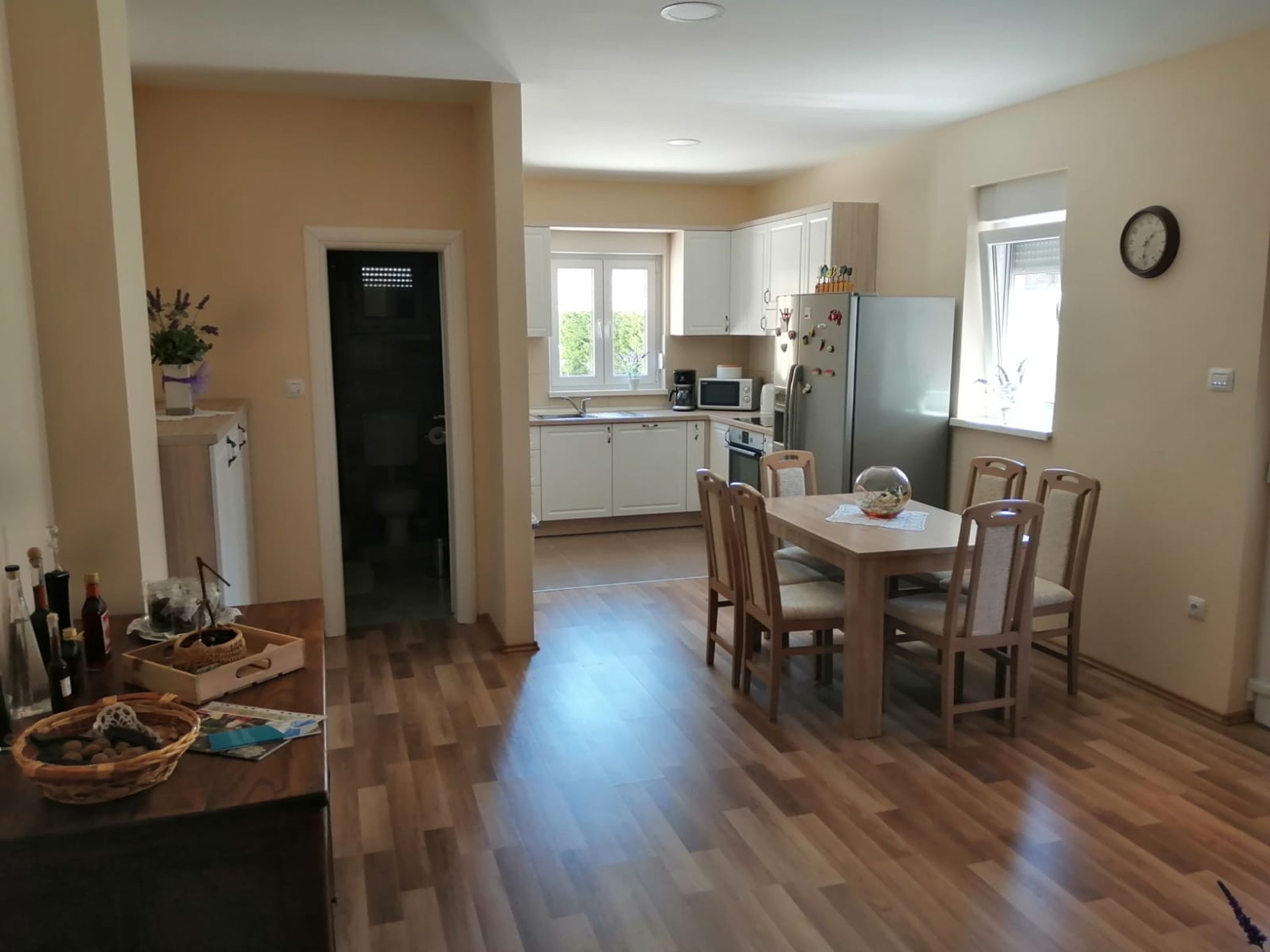 Une cuisine moderne avec des meubles en bois, une table à manger avec des chaises et un réfrigérateur.